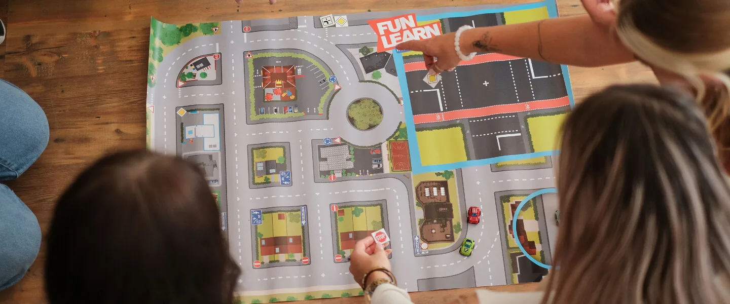 Fahrschülerinnen arbeiten im FUN-LEARN-Unterricht an einer Straßenkarte mit Modellfahrzeugen